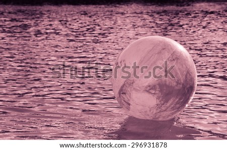 concept image for global environmental issue using inflatable rubber ball with earth like markings and rippled water surface