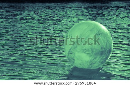 concept image for global environmental issue using inflatable rubber ball with earth like markings and rippled water surface