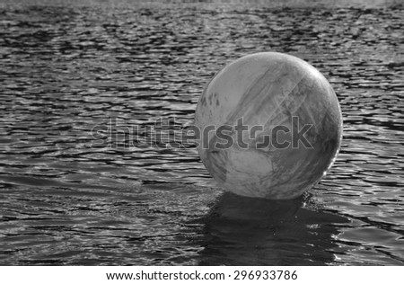 monochromatic concept image for global environmental issue using inflatable rubber ball with earth like markings and rippled water surface