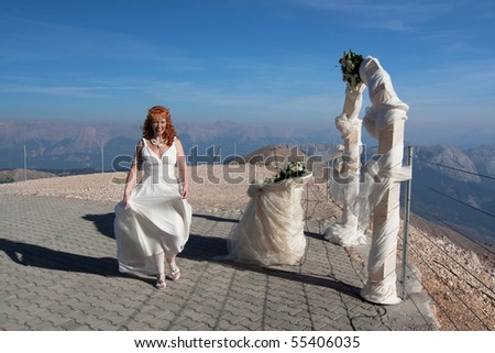 A laughing bride goes ahead beside the wedding arch and altar