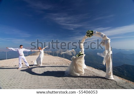  The newlyweds poses near the wedding arch and altar against the blue sky