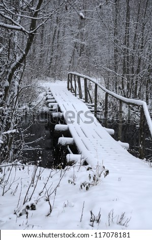 Wooden bridge over dark river in the countryside in Russia in the winter