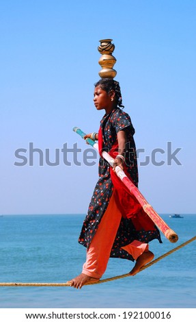 GOA, INDIA - NOVEMBER 23, 2007: Young Indian female tightrope walker performs for fun on the beach.