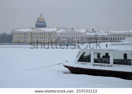SAINT PETERSBURG, RUSSIA - JANUARY 9, 2009: View of Saint Isaac\'s Cathedral, the frozen Neva river and ice-bound motor boat on a gloomy foggy winter day