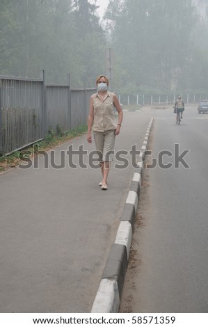 YUBILEINY, MOSCOW REGION, RUSSIA - AUGUST 6: Woman is walking down empty street in thick smoke with a mask on her face August 6, 2010 in Yubileiny, Moscow region, Russia. Smoke was caused by wildfires