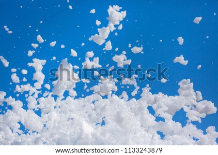 White soap foam on a blue sky background. Fun foam, background or texture of a white foam with copy space Entertainment foamy parties a summer entertainment festival in the water park