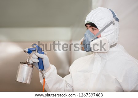 A man in a protective suit in the laboratory conducts disinfection. Specialist clothing protecting from chemical poisoning in the industry and treatment with insecticides.