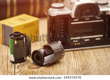 Old film camera and roll films on the wooden background. Low depth of field. Tinted image.