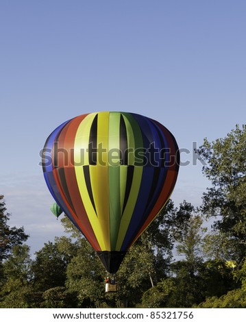 Colorful hot air balloon prepares to land.