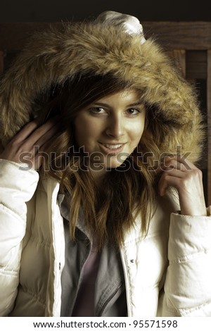 Beautiful young woman in white parka warms up after being outdoors.