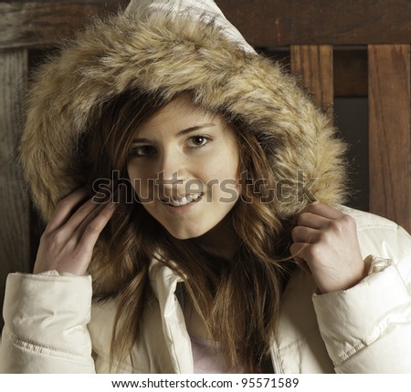 Beautiful young woman in white parka warms up after being outdoors.