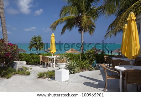 Tables and yellow umbrellas by the blue-green water of Grace Bay Beach, Providenciales, Turks and Caicos Islands.
