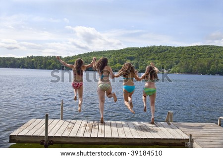 holding hands jumping. stock photo : Four teenage girls jumping off a dock at a lake, holding hands