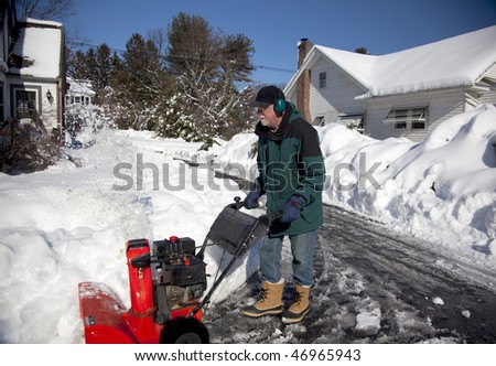 Middle-aged man pushing a bright red snow blower