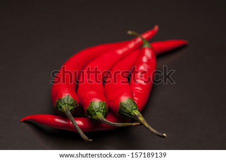 Four Red Chillies on a Grey Reflective Surface