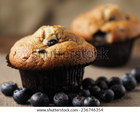 Blueberry muffins close up, against a rustic background with blueberries spread on the table