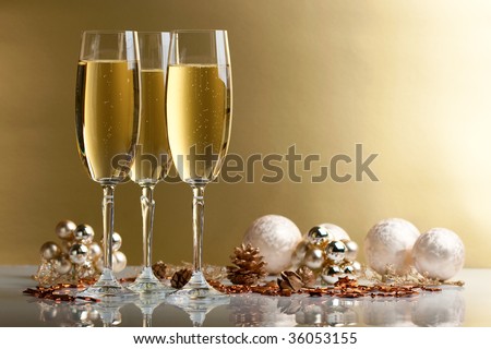 three glasses of champagne, christmas balls and ornaments in front of golden background