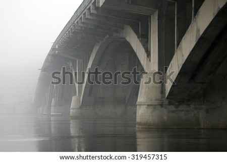Concrete arch bridge over the river in the fog