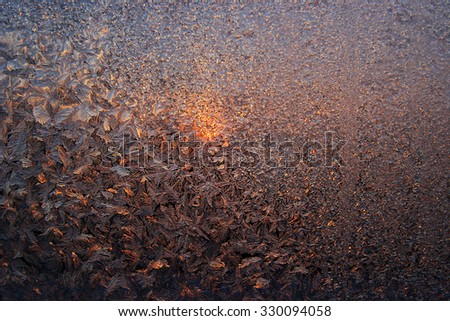 The sun is shining through the frosted glass. Frosty pattern on the frozen stained glass