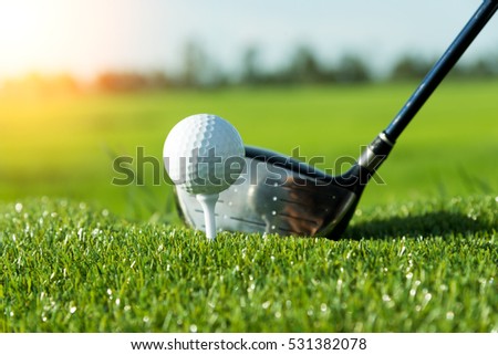 Golf club and ball in grass and sunset