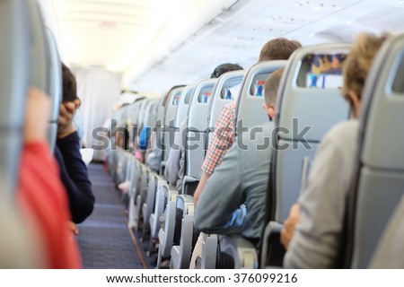 Passengers are sitting and sleeping on an airplane. They get stuck in their seat in a long and boring flight.