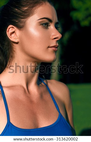 Beautiful fitness athlete woman resting after work out exercising on summer evening in lawn at sunset outdoor portrait