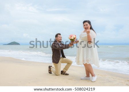 Will you marry me concept, Asian man on his knees asking his girlfriend to marry on the beach.