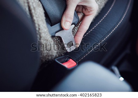 Close-up of woman hand fastening a seat belt in the car