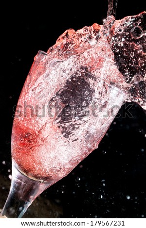 Red wine splashing out of glass, on a black background