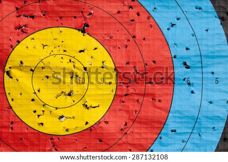Archery target close up with many arrow holes in gold red blue and black