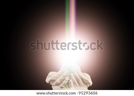 Spiritual light in cupped hands on a black background