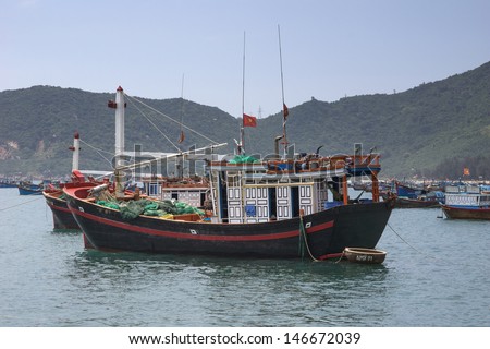 Focus on one fishing boat among many moored in front of village in Central Vietnam. Colorful and detailed sight of a typical fishing vessel anchored in the South China Sea.