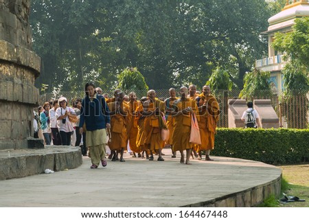 SARNATH, INDIA - CIRCA FEBRUARY 2011: Buddhist monks, followed by pilgrims, circle the Dhamekh Stupa in the birthplace of Buddhism.