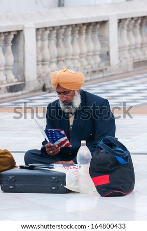 NEW DELHI, INDIA - CIRCA MARCH 2011: Sikh emigrant, sitting on the pavement, studies how to get legally into the USA. As seen on the grounds of the Gurudwara Bangla Sahib, the leading Sikh Temple.