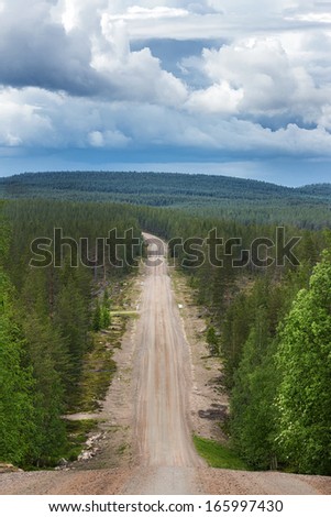 Road cuts through the forest in eastern Lapland. Dirt roads like these are the main link between towns and villages, and sometimes the road needs to climb steep hills.