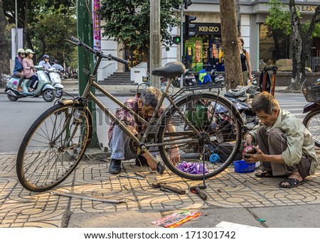 HANOI, VIETNAM - CIRCA MARCH 2012: Bike repair business on a corner of the street.Small free enterprise vendor working on bicycle.