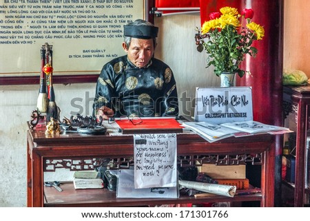HANOI, VIETNAM - CIRCA MARCH 2012: Old man offers calligraphy in Ngoc Son temple. Staring as if he was a puppet but the cigarette gives him away.