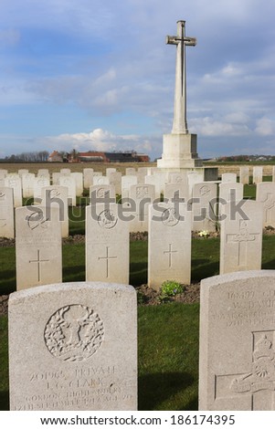 IEPER, BELGIUM - CIRCA MARCH 2014: Belfry of Ypres (Ieper) with Flanders Fields Museum. Tomb stones and the cross at Bard Cottage Cemetery at Ypres, Flanders, Belgium.