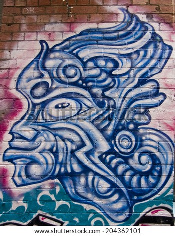 MELBOURNE, AUSTRALIA - CIRCA NOVEMBER 2009: Colorful graffiti in back alley of downtown, depicts a fierce looking, blue, all-lined male mask.