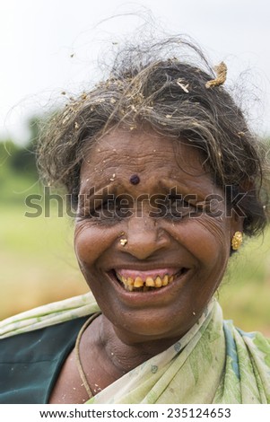 KUMBAKONAM, INDIA - OCTOBER 10, 2013: Close-up of older woman farmer with bad teeth and millet husks in her graying hair.