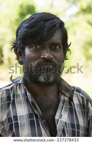 KUMBAKONAM, INDIA - OCTOBER 11, 2013: A stern-looking Hindu man looks into the camera, showing off his pitch black hair and graying beard.