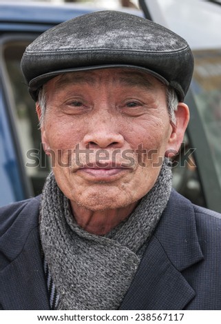 VINH, VIETNAM - MARCH 15, 2012: Closeup of older Vietnamese man with gray-black had and a thick shawl under his jacket.