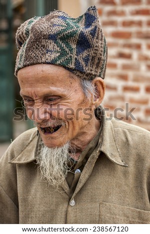 HANOI, VIETNAM - MARCH 8, 2012: An old man, claiming to be in his eighties and a French teacher has extremely bad black teeth.