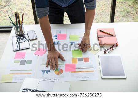 Asian business man hand holding note paper meeting with new startup project use post it notes to share idea discussion and analysis data charts and graphs.Business finances and accounting concept
