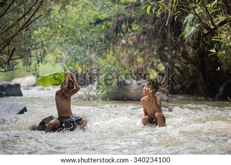 Udon Thani Province, Thailand - November 8: Two boys play in the water on November 8, 2015, in Udon Thani Province, Thailand.