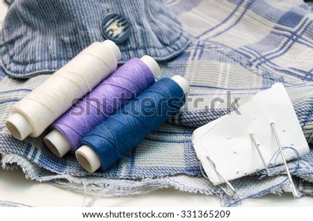 needles and threads on white and blue material background
