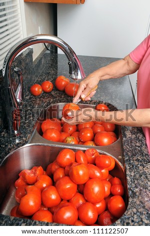 A woman prepares tomatoes for canning by removing the core of the tomato.