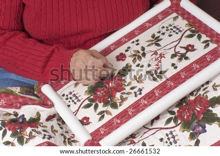 A woman hand quilts a new quilt using a plastic frame.