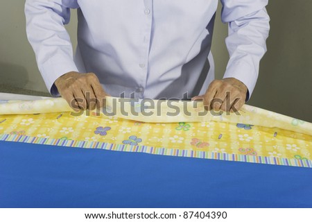 A woman rolling fabric to create a tubular pillow case.