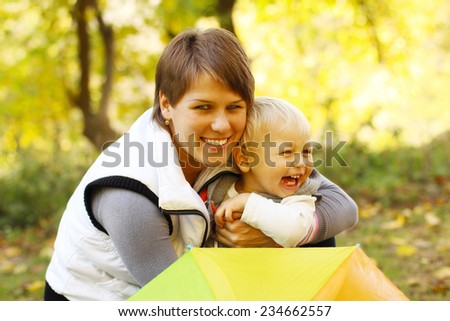 Mother with baby in the park under an umbrella